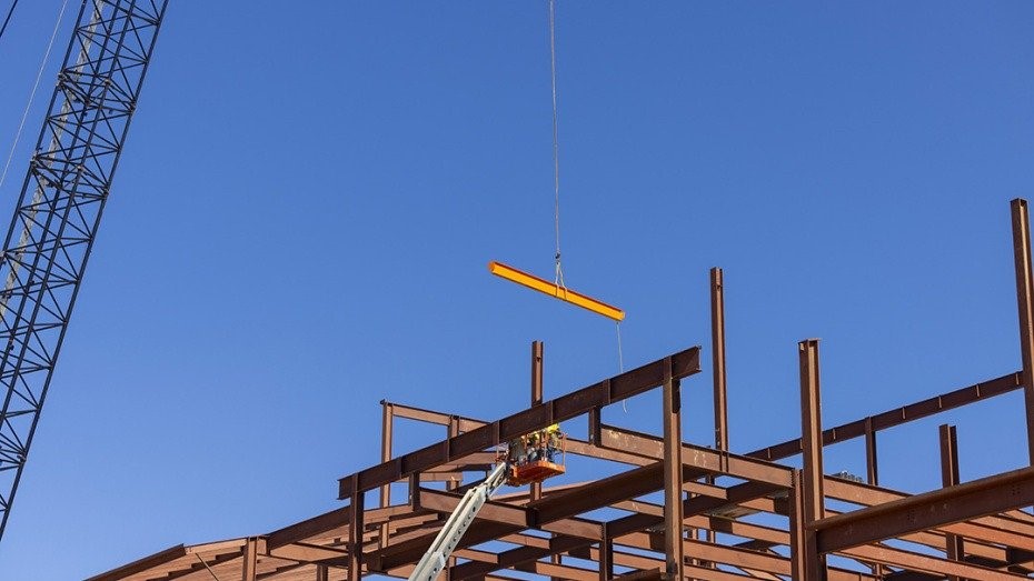 Construction company erecting structural steel frame with crane